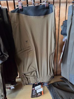many jackets and pants hanging on a rack in a store