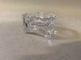 un petit objet en verre posé sur une table, sur fond blanc