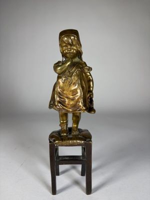 figurine en laiton représentant un enfant assis sur un tabouret