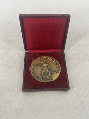 a gold medal in a red box on a white surface