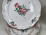 three plates with flowers on them sitting on a table