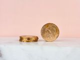 a gold coin sitting on top of a marble slab next to a pink background