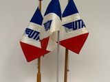 trois drapeaux posés sur un support posé sur une table