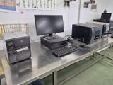 trois ordinateurs et une imprimante posés sur une table dans une pièce