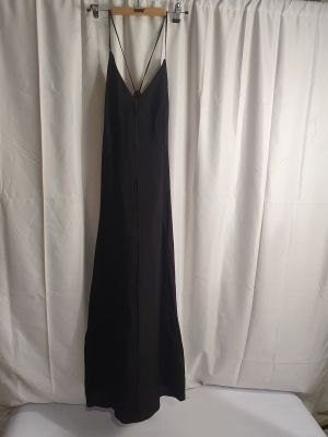 une robe noire suspendue à un cintre devant un rideau blanc