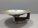 a silver plate on a wooden stand on a white surface