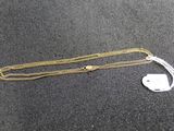 a gold chain with a tag attached to it on a black surface