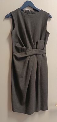 robe grise sans manches avec une ceinture, suspendue à un cintre accroché au mur