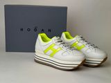 the white and yellow sneakers are next to a blue box