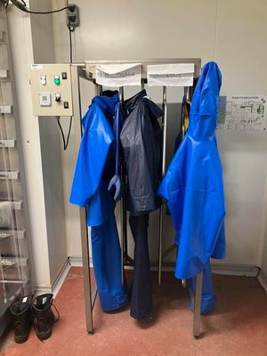 trois imperméables bleus suspendus à un porte-manteau dans une pièce