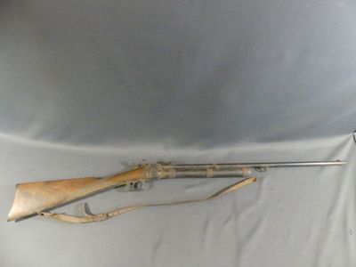 an old rifle is laying on a white sheet on a table