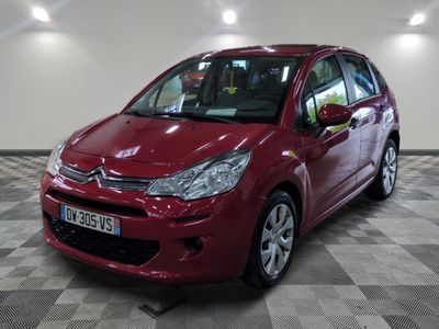 La Citroën rouge est garée sur un sol en damier dans un garage.