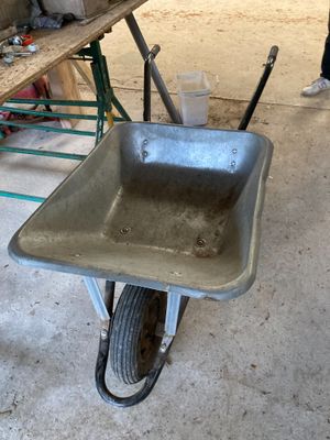 une brouette au milieu d'une pièce, avec des outils posés sur la table