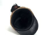 hat with fur pom poms on top of it on a white surface