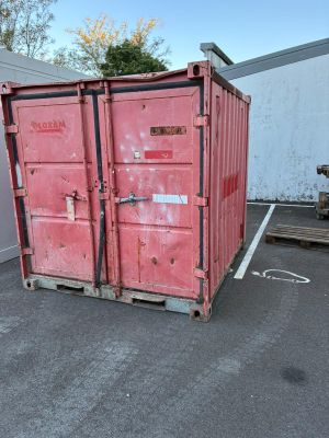 a red container sitting in a parking lot next to a building