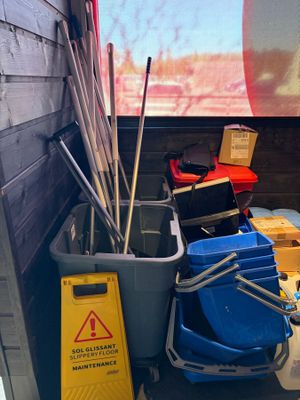 several buckets and brooms are lined up in the corner of a room