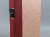 a book with a red cover and gold trim sitting on top of a table