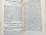 an open book with black writing on it sitting on top of a table