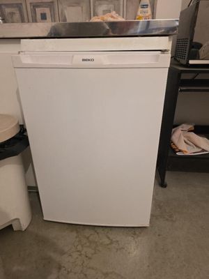 un lave-vaisselle blanc posé dans une cuisine à côté d'une poubelle