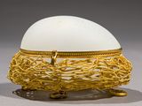 a white egg sitting on top of a gold wire basket