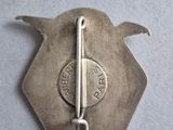 an old silver pin with a pin on it sitting on a table