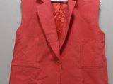 a red vest is hanging on a hanger on a wall