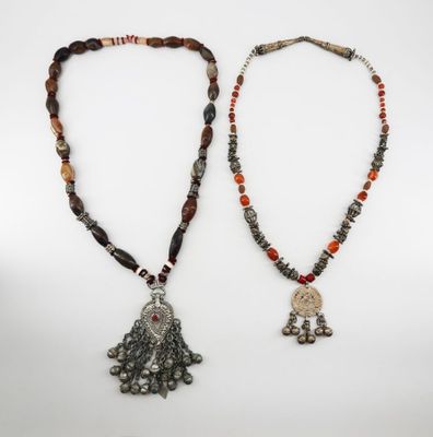 two necklaces with beads and a silver pendant on a white background