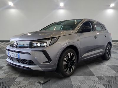 Une voiture argentée est garée dans une grande pièce au sol carrelé en damier.
