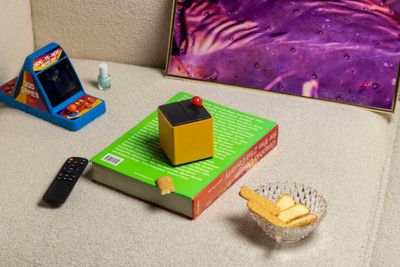 a picture of a book, a remote control, and a box on a couch