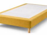 yellow upholstered bed frame with wooden legs and a white sheet on top