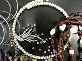 many different types of necklaces and bracelets on a table