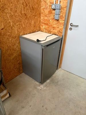 un petit réfrigérateur dans un coin de la pièce