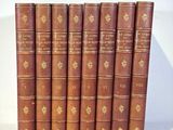 six old books are lined up on a white surface
