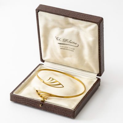 une image représentant un bracelet en or dans un écrin, sur fond blanc