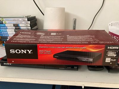 un lecteur DVD Sony posé sur un bureau, à côté d'une pile de DVD