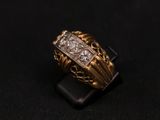 a close up of a gold and diamond ring on a black surface