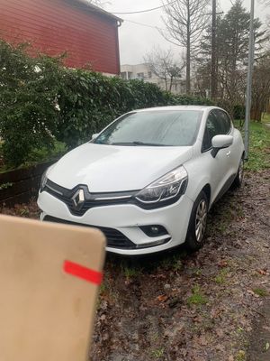 La voiture est garée sur le bord de la route, à côté d'un carton.
