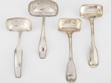 trois cuillères en argent et une spatule posées sur un plan de travail blanc