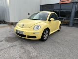 une Coccinelle Volkswagen jaune garée devant un immeuble, sur un parking