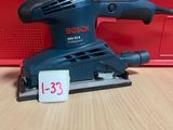 La ponceuse orbitale Bosch est posée sur une table, à côté d'une boîte rouge.