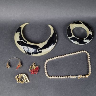 un collier, un bracelet et une bague noirs et blancs posés sur une table
