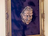 a painting of a man ' s face hanging on a wall