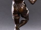 a bronze statue of a man holding a tennis racquet