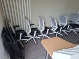 Plusieurs chaises de bureau sont alignées en rang dans une pièce vide