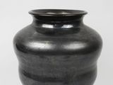 a black vase that is sitting on a white surface