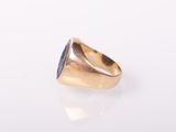 a gold signet ring with a black stone in the center