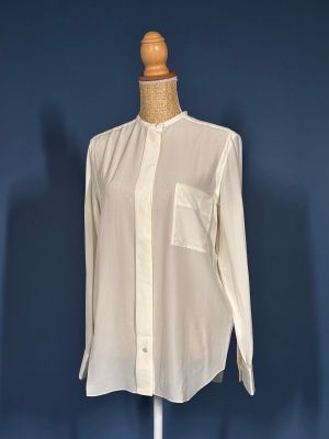 a white shirt on a mannequin stand against a blue wall