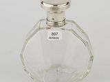 a glass bottle with a silver lid on a white surface