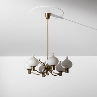 un lustre en laiton muni de cinq abat-jours en verre blanc suspendu au plafond