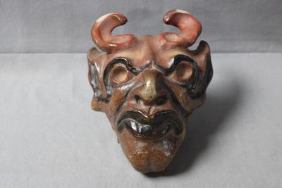a ceramic sculpture of a demon head on a table